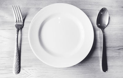 Directly above shot of empty plate with fork and spoon on table