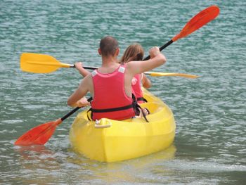 Rear view of people enjoying in sea