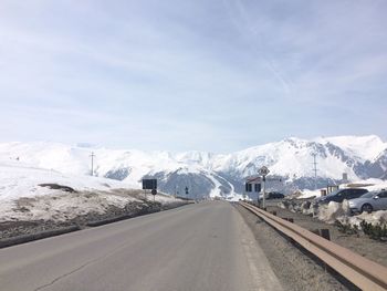 Road by mountains against sky during winter