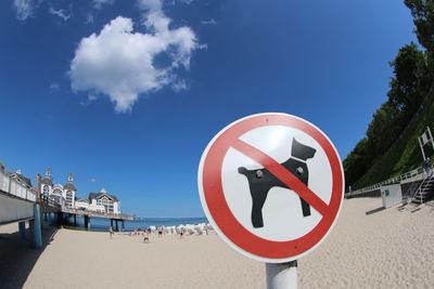 Close-up of road sign on beach against blue sky