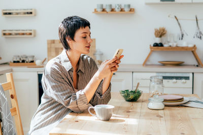 Portrait of young woman using mobile phone at home