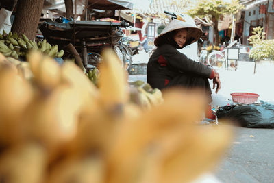 Close-up of bananas with woman sitting in background