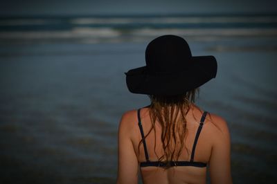 Rear view of woman wearing hat standing on beach