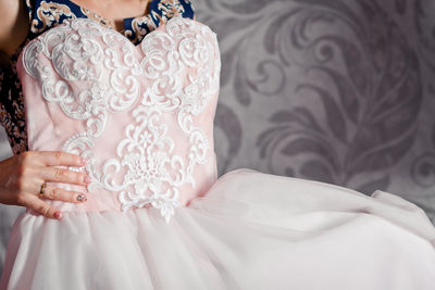 Midsection of tailor holding wedding dress