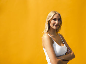 Portrait of smiling young woman against yellow background