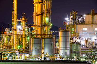 Illuminated factory against sky at night