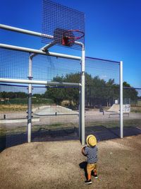 Rear view of boy with basketball standing at court