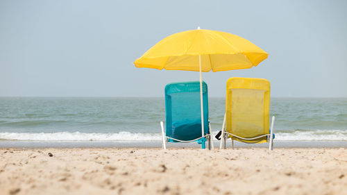 Yellow umbrella on beach against clear sky