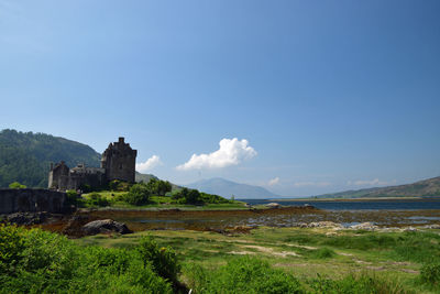 Scenic view of building and mountains against blue sky