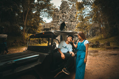 Full length of couple by vintage car against trees