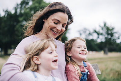 Happy mother sitting with daughters at park