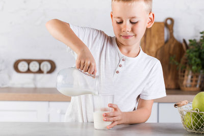 Cute boy pouring milk in glass