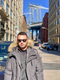 Portrait of young man wearing sunglasses standing in city