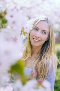 Beautiful woman looking away while standing by white blossoms