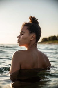 Young woman looking at swimming pool against sky