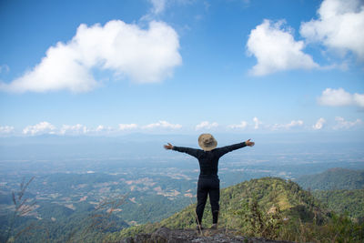 Rear view of man with arms outstretched against sky