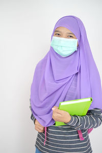 Portrait of a young woman standing against white background