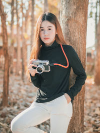 Portrait of teenage girl photographing in forest