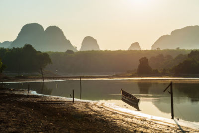 Float wooden boat on nong thale lake swamp at sunrise with limestone mountains, krabi, thailand. 