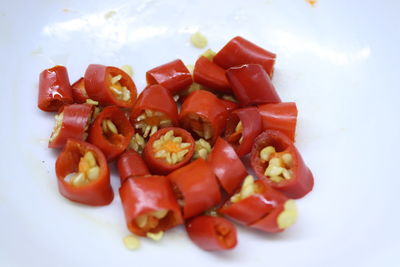 Close-up of fresh red chili peppers in plate against white background