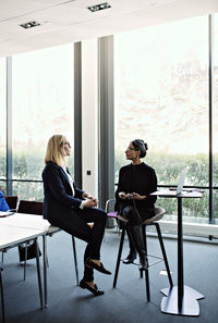 Businesswoman discussing with female colleague on chair