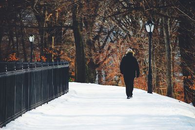 Rear view of woman walking on snow covered road