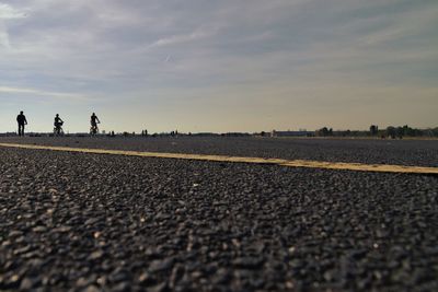 Surface level of people walking on road against sky