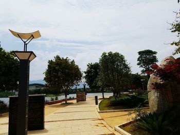 Street light by footpath in park against sky