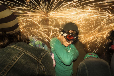 Midsection of man with fire crackers at night