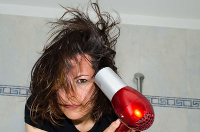 Portrait of woman holding hair dryer