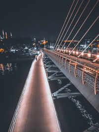 Illuminated bridge over river in city at night