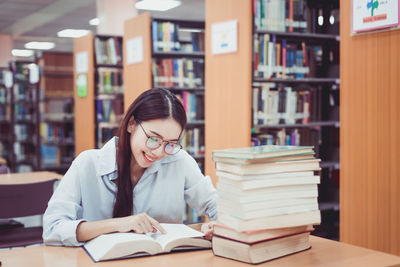 Beautiful young woman reading book in library