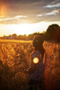 Rear view of woman on field at sunset