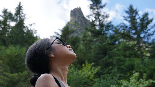 Side view of woman looking away against trees