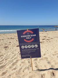 Information sign on beach against clear sky