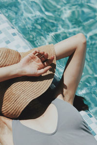 Low section of woman sitting by swimming pool