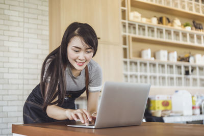 Young woman using phone while sitting on table