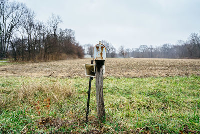 Wooden post on field against sky