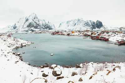 Scenic view of sea by snowcapped mountains against sky