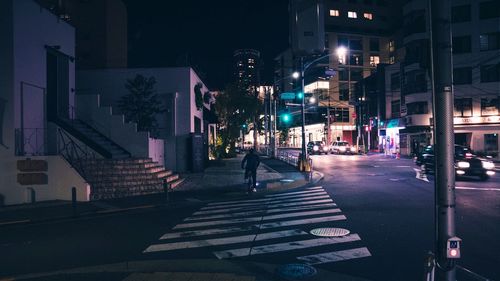 Empty narrow road along buildings at night