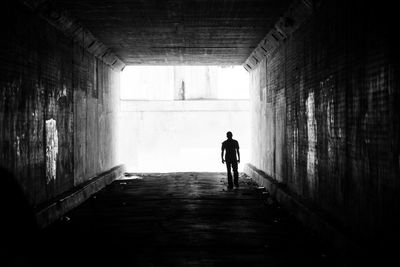 Rear view of woman walking in tunnel