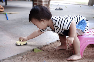 Cute boy playing with toy car while sitting on seat