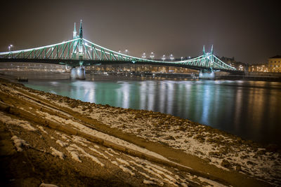 Illuminated bridge over river at night