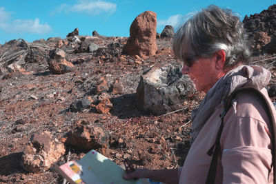 Side view of senior woman reading map while standing on land