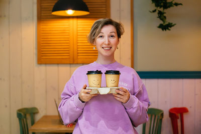 Portrait of smiling woman holding coffee cup at home