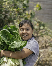 Portrait of young woman standing against plants