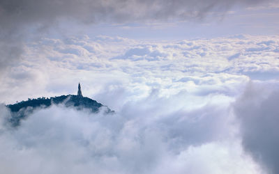 Aerial view of communications tower on hill against clouds
