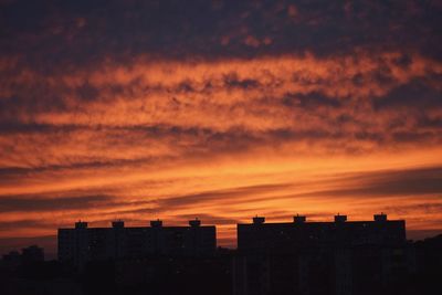 Silhouette buildings against dramatic sky during sunset