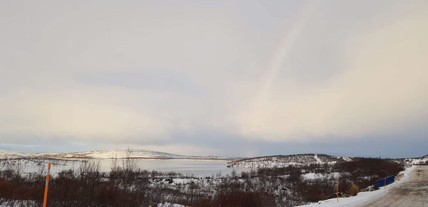 Scenic view of rainbow over snowcapped mountains against sky