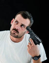 Man attempting suicide with gun against black background